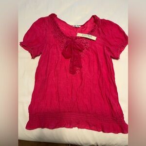 Bright pink blouse with crochet decorations and chiffon tie. Elastic bottom.